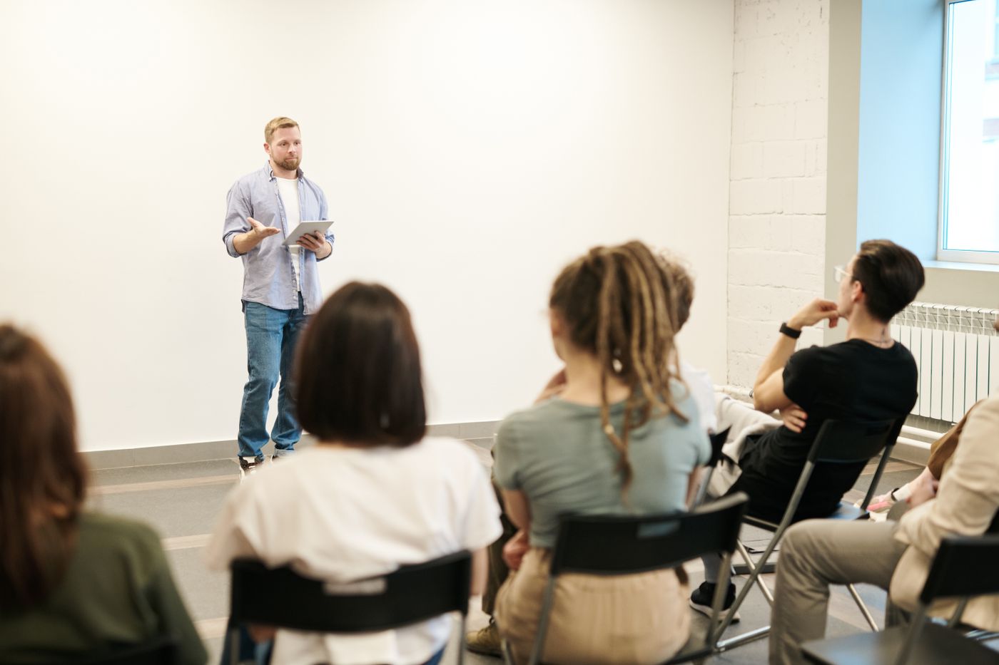 An instructor standing and leading a session while students work at their tables